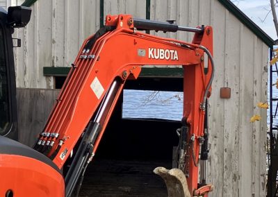 2023-12-06 Tis the Season, photographed by Beverly Crofoot on Bay Street in Bayside, ME, where this excavator looks suspiciously close to the garage of the Braking Wind cottage. Nice view, though. #renovations #fixingup #cottagelife #kubota #penobscotbay #baysidemaine