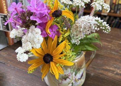 2025-07-29 Books and Blossoms, photographed at the Bayside, ME Library by Cookie Santerre. “Such a nice welcome in the Bayside Library. Thank you.” The library/ located at George and Clinton, is open 10-5 daily. Thank you to the volunteers who make this resource available to the community. Donations that are in excellent condition are welcomed. #library #baysidelibrary #books #blossoms #flowerarrangement #baysidemaine
