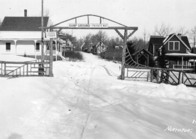 2025-12-22 No Plow Zone, submitted by Beverly Crofoot on behalf of the Bayside Historical Preservation Society (www.baysidehps.org) and showing an undated winter view of the south entrance to Bayside, ME (on George Street), with Bayview Park to the left and right just beyond the gate. There used to be a 10- cent entrance fee starting in 1870. (The wharf was built in 1874.) Please consider joining the BHPS at https://baysidehps.org/. #tbm #noplowzone #snowyroad #winter #entrygate #bayviewpark #oldbayside @baysidehps #bhps #baysidemaine